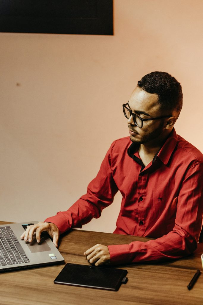 Homem de camisa vermelha trabalhando em um notebook